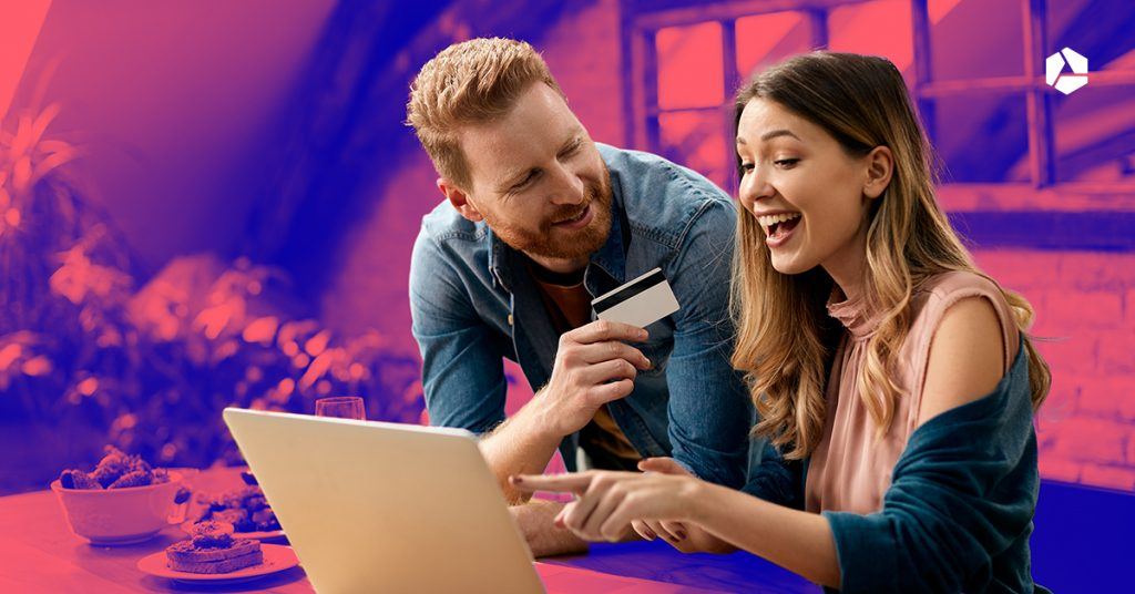 A man and woman behind a laptop holding a bank card.