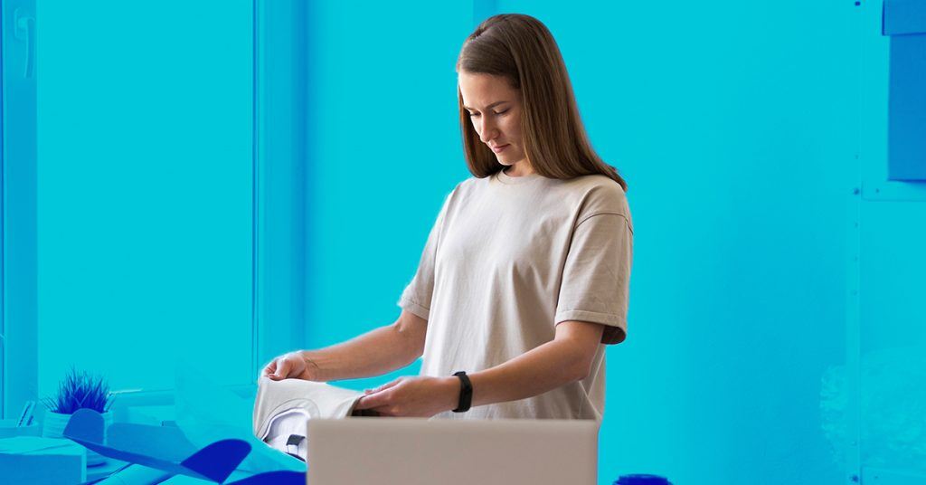 Having your own online shop also requires a good shipping and returns policy A woman packing her webshop orders to ship.