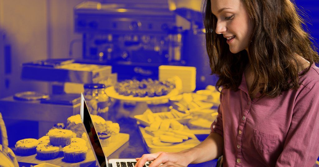 Publish your own webshop relatively cheaply and easily A webshop owner who cheaply and easily builds her webshop on her latop, surrounded by her homemade cakes and pies.