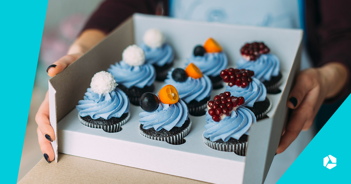 Een vrouw die een doos met negen cupcakes vasthoudt.